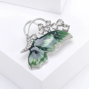 Macro detail of enamel butterfly brooch with green wings and sparkling rhinestones