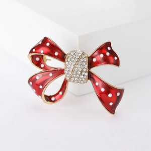 Vue détaillée d'une broche noeud en émail rouge à pois blancs avec centre en strass