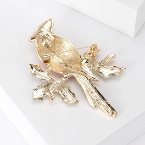 Broche oiseau dorée avec détail de l'épingle arrière et finition en métal brossé chic
