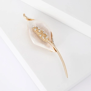 Détail d'une broche calla lily dorée avec pétales nacrés et cristaux étincelants
