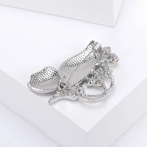 Macro shot of silver butterfly brooch back showing secure safety pin clasp and metal texture