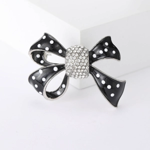 Broche nœud en émail noir à pois blancs et cristaux sur support géométrique blanc