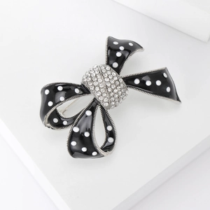 Détail macro de la broche nœud en émail à pois blancs et centre en strass brillant