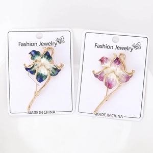 Detail view of colorful enamel orchid flower brooches with golden metal finish and stems