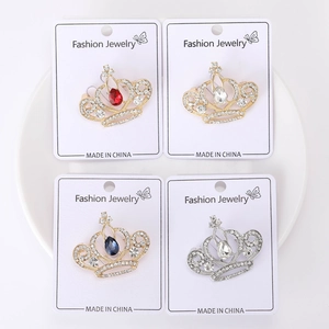 Gros plan de broches couronnes en cristal coloré avec strass blancs sur plateau céramique