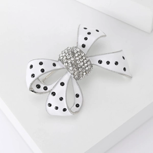 Détail macro d'une broche nœud en émail avec pois noirs et strass scintillants
