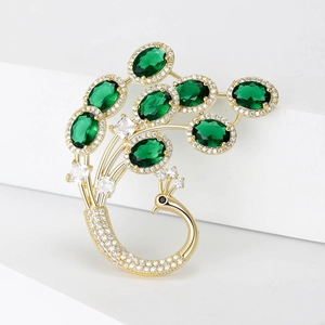 Détail d'une luxueuse broche paon dorée avec pierres vert émeraude et cristaux