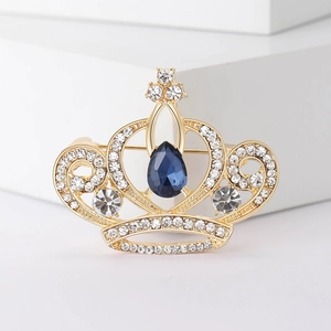 Élégante broche couronne dorée avec strass brillants et pierre bleue en forme de poire