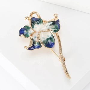 Detail view of gold-plated enamel peach blossom brooch with blue marble texture petals