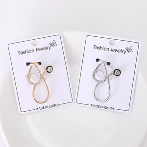 Detailed view of stethoscope brooches with sparkling crystals and black enamel in gold and silver
