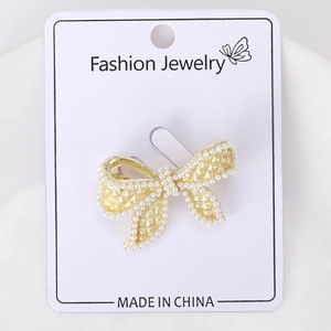 Close-up of golden bow brooch with elegant lattice texture and inlaid white pearls
