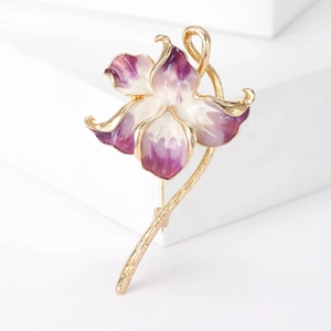 Close-up of peach blossom brooch with purple enamel petals and gold stems on white stand
