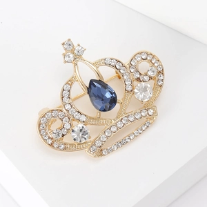 Détail d'une broche couronne dorée avec cristal bleu et strass blancs scintillants