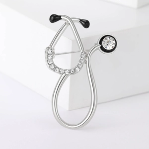 Macro shot of silver stethoscope brooch with rhinestones and black enamel detail