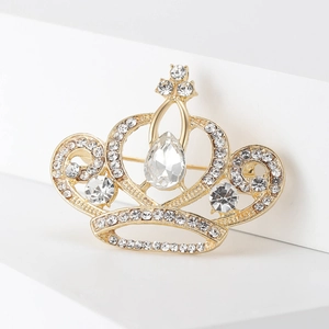 Détail d'une broche couronne en cristal avec base dorée et pierre en forme de goutte