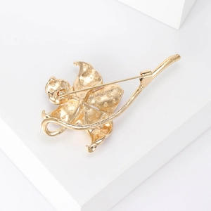 Elegant gold peach blossom brooch with rotating safety pin clasp on white block