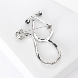 Macro shot of silver-tone stethoscope brooch with black accents and pin fastening