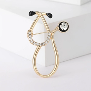 Detailed view of stethoscope brooch with gold alloy finish and sparkling rhinestones