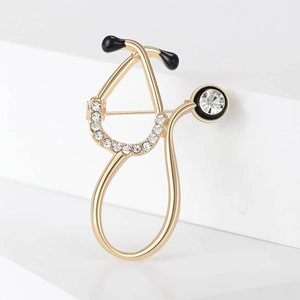 Golden stethoscope brooch with clear rhinestones and black enamel on white display