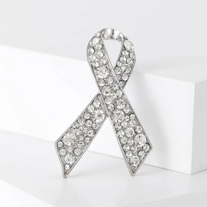 Gros plan d'une broche nœud argentée ornée de strass brillants sur socle blanc