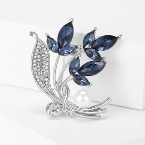 Detailansicht der silbernen Orchideen-Brosche mit blauen Kristallen und einer weißen Perle
