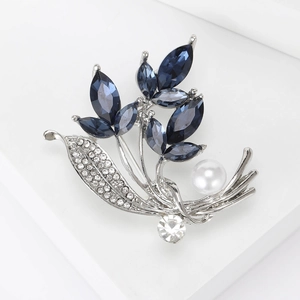 Nahaufnahme der blauen Orchideen-Brosche mit weißen Kristallen und Perlendetail