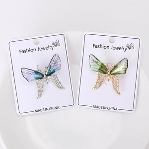 Detailed macro of rhinestone butterfly brooches with acrylic wings on a white card
