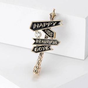 Vue détaillée d'une broche panneau doré avec lettrage Happy Kiss et strass brillant