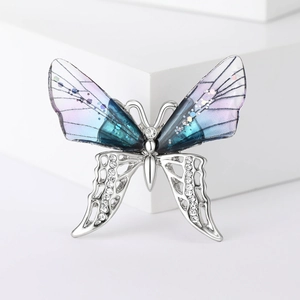 Detailed view of rhinestone butterfly brooch with blue gradient and silver metal wings