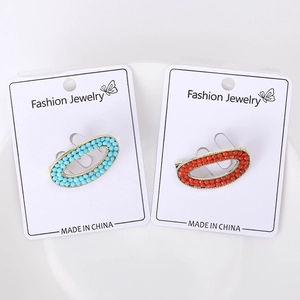 Detailed macro view of bohemian oval brooches with sky blue and brick red beads in gold finish