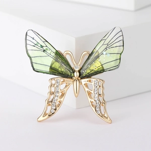 Macro shot of butterfly brooch with green gradient wings and sparkling rhinestones