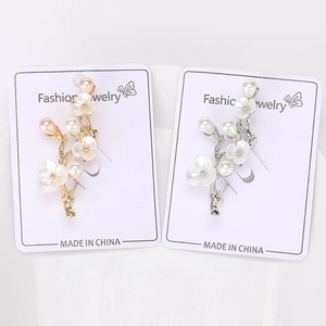 Detail of elegant peach blossom branch brooches in gold and silver metal with pearls