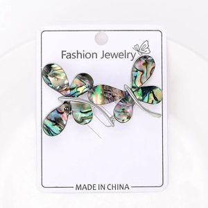 Detailed macro view of vintage butterfly brooch with abalone shell inlays on jewelry card