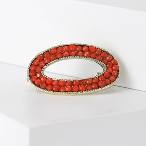 Detailed macro view of vintage gold oval brooch with double rows of red faceted beads