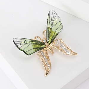 Detailed macro shot of a butterfly brooch with green resin wings and sparkling rhinestones