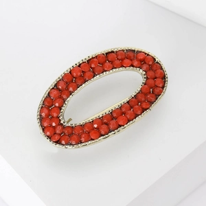 Detail shot of oval gold alloy brooch with vibrant red faceted rhinestones for sweaters