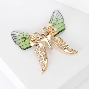 Close-up of golden insect brooch back showing pins and translucent green wing texture