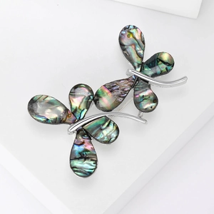Elegant silver butterfly brooch with colorful abalone shell inlays on a white pedestal