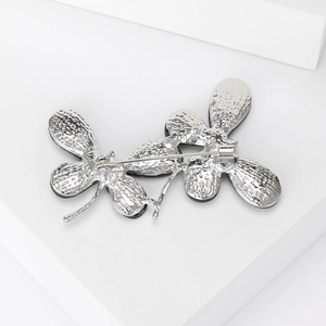 Elegant silver flower brooch pin with detailed metallic leaf texture on white pedestal