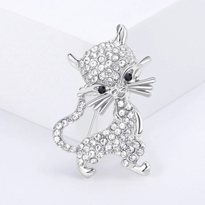 Macro detail of silver cat brooch with white rhinestones on minimalist white display