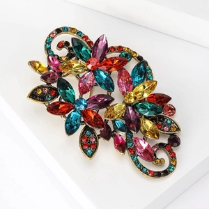 Detail showing vintage gold-tone flower brooch with multi-colored crystals on white props