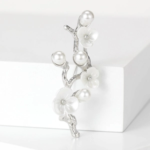 Detailed macro view of elegant plum blossom brooch with pearls on a silver branch