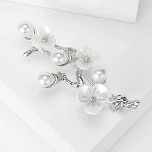 Detail view of flower brooch with white pearls and frosted petals on silver stem branch
