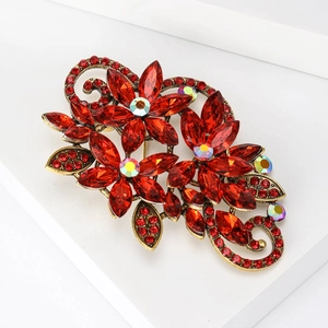 Close-up of vintage floral brooch with red marquise crystals and antique gold finish