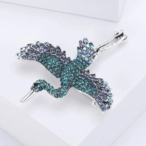 Detailed macro view of flying crane brooch with blue and green rhinestones