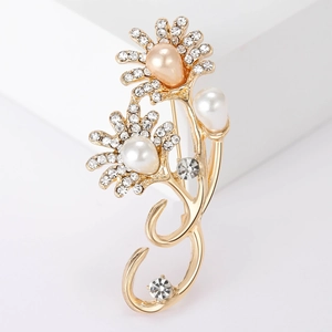 Elegant gold flower brooch featuring sparkling rhinestones and teardrop pearls on a white stand