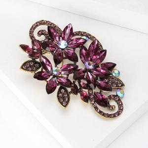 Detailed macro view of a vintage floral brooch with purple crystals and bronze alloy base