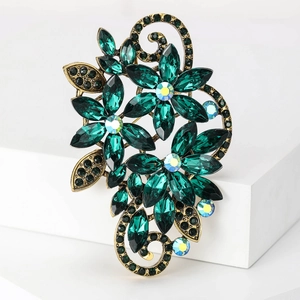Close-up of vintage flower brooch with green crystals and antique gold vine details