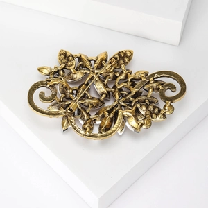 Detailed close-up showing the vintage gold crystal brooch with intricate filigree texture