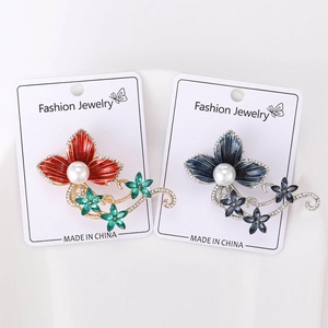 Detailed macro view of rhinestone flower brooches with pearl accents on card
